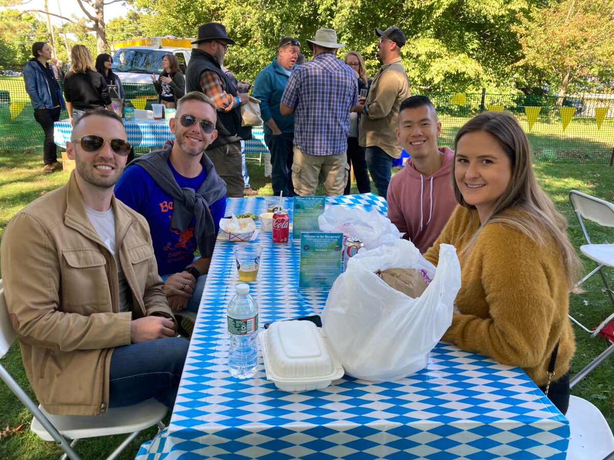 Four people sitting at checkered table at an outdoor beer garden.